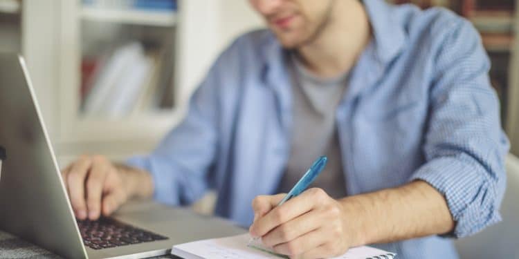 jeune homme travaillant chez lui sur un ordinateur portable